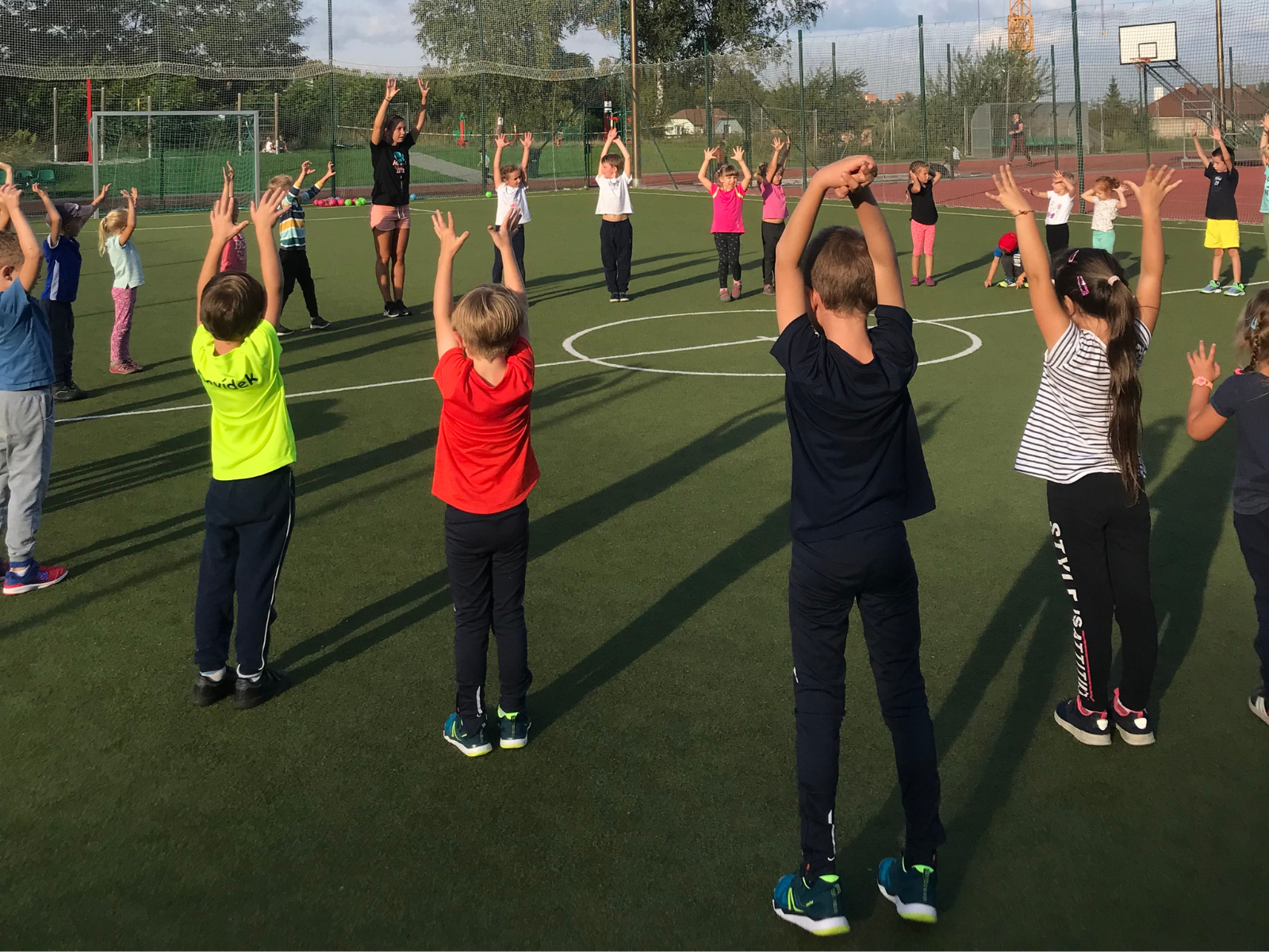Děti s rukama ve vzpažení na venkovním sportovišti